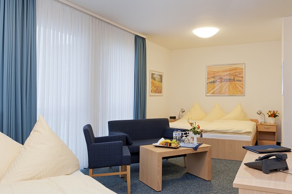 Familienfreundliches Dreibettzimmer mit Bett, Sofa und Sitzbereich.