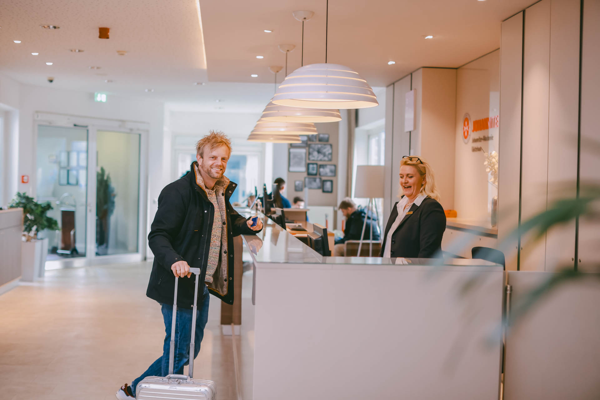 Gast mit Koffer beim Check-in an der Rezeption