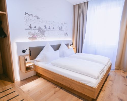 Modern standard double room with warm wood details and a calm atmosphere.