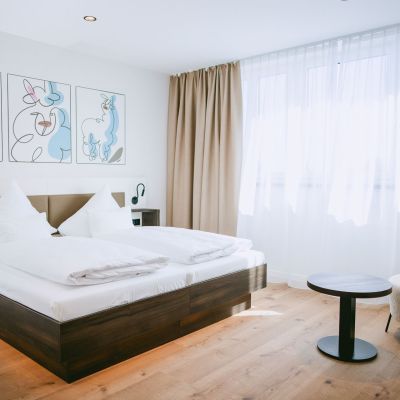 Komfort Familienzimmer mit Doppelbett, Sessel und kleinem Tisch.