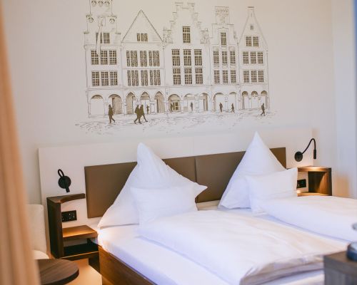 Stylish sleeping area with a comfortable double bed, reading lamps and decorative wall artwork