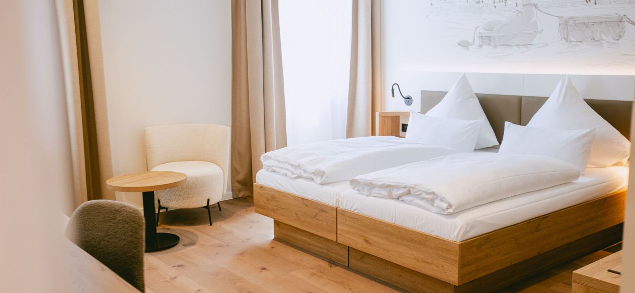 Zimmer mit Bett, Sitzbereich und Schreibtisch.