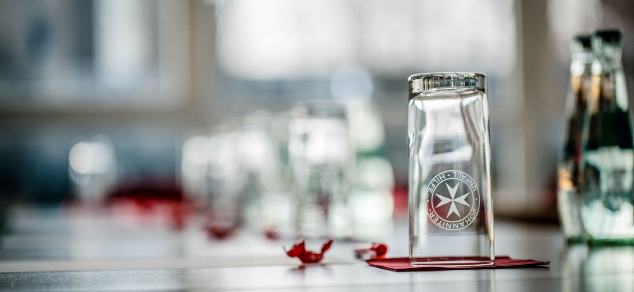 Wasserglas und Flaschen auf einem gedeckten Tagungstisch.