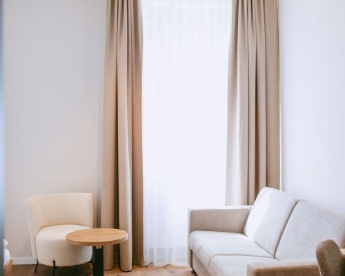 Modernes Standard-Doppelzimmer+2 mit Doppelbett, Holzboden, Sitzecke und Wandmotiv.
