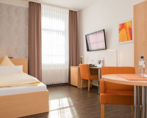 Standard single room with single bed, desk, seating area and large window