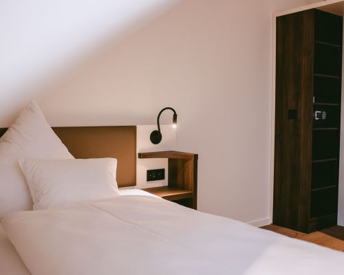 Peaceful sleeping area with a comfortable single bed, reading lamp and warm wood details