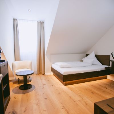 Komfort Einzelzimmer mit Bett, Schreibtisch und Sitzplatz am Fenster.