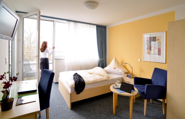 Single room with balcony, bed, desk and seating area
