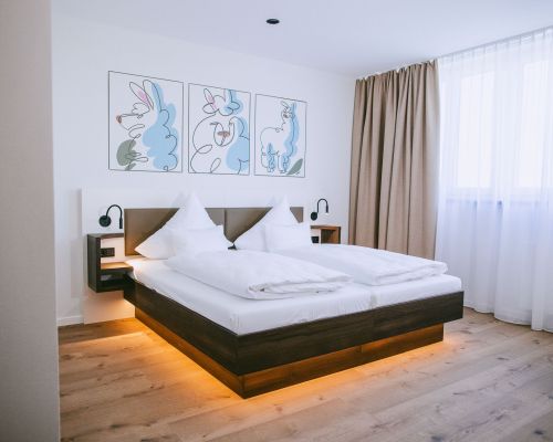 Bright comfort family room with a cozy double bed, warm wooden flooring and a welcoming atmosphere.