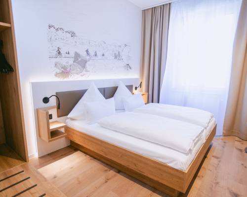 Modernes Standard-Doppelzimmer im Johanniter Gästehaus Münster mit Doppelbett, Holzboden und Fenster.
