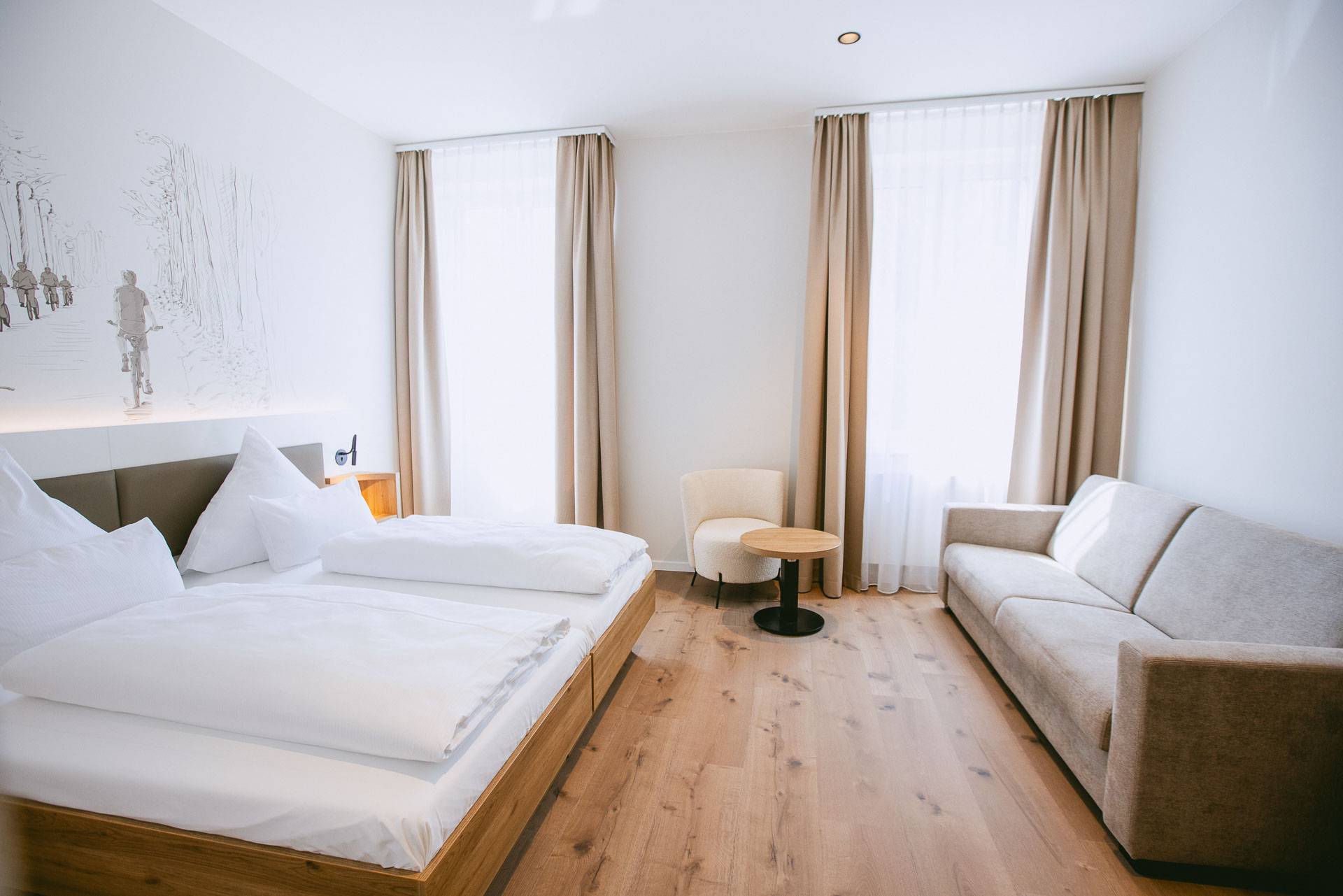 Helles Doppelzimmer mit Doppelbett und Sitzgelegenheit