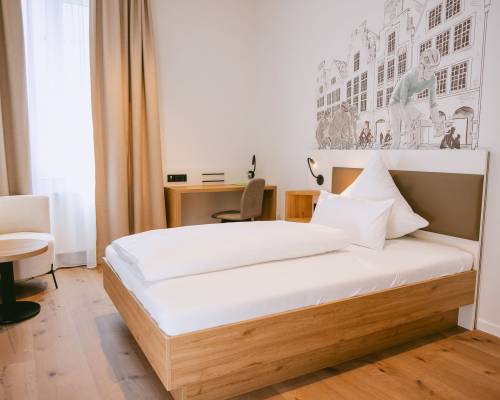 Standard Einzelzimmer mit Einzelbett, Schreibtisch und modernem Holzboden im Johanniter Gästehaus Münster