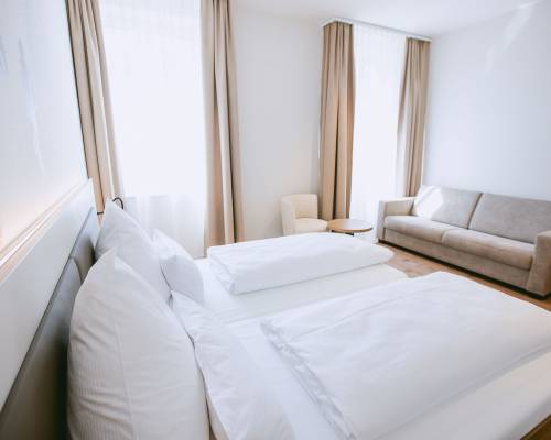 The room offers a spacious sleeping area and a comfortable seating option for relaxing moments